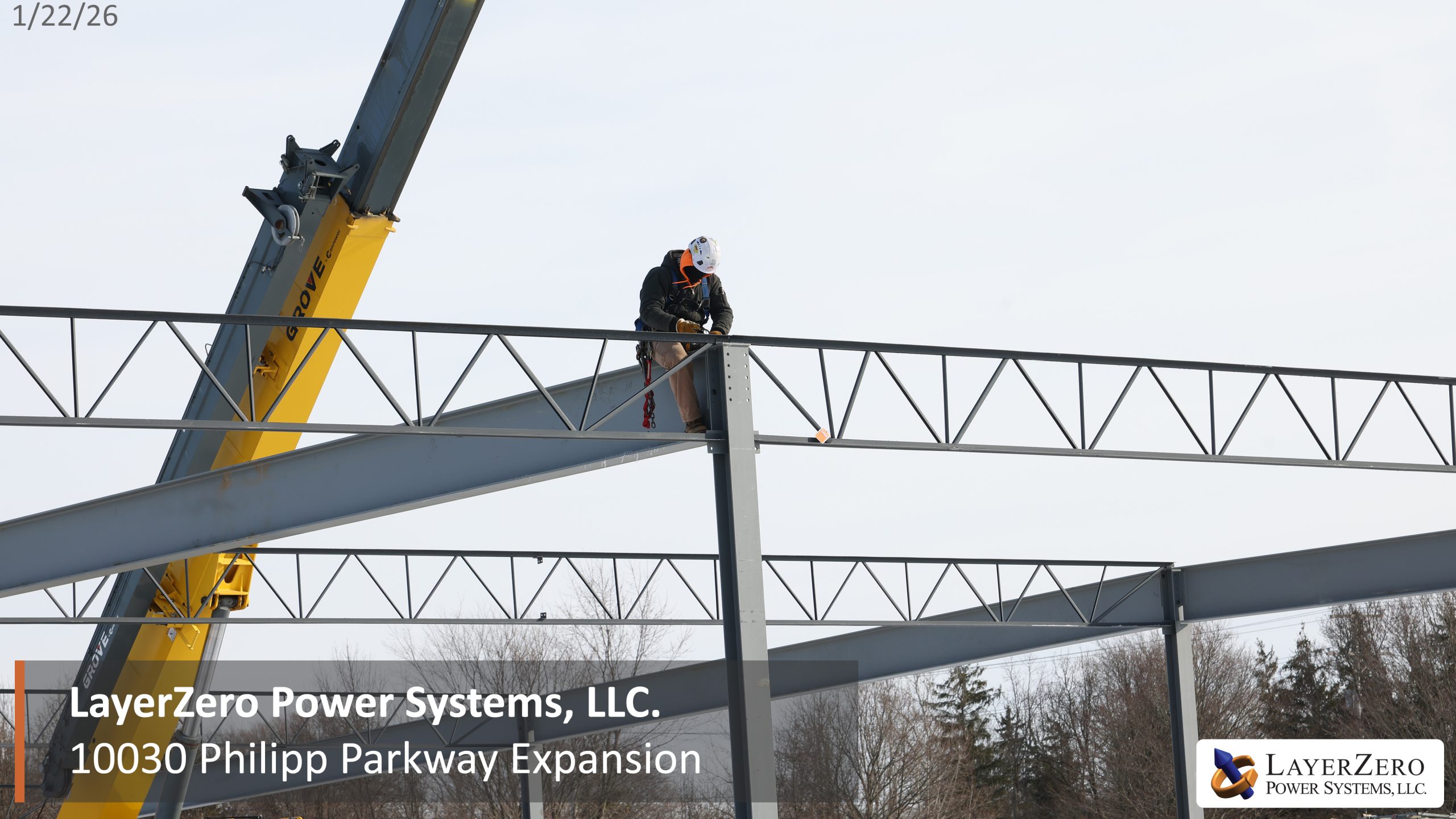 Construction worker installing steel roof truss during LayerZero Power Systems facility expansion