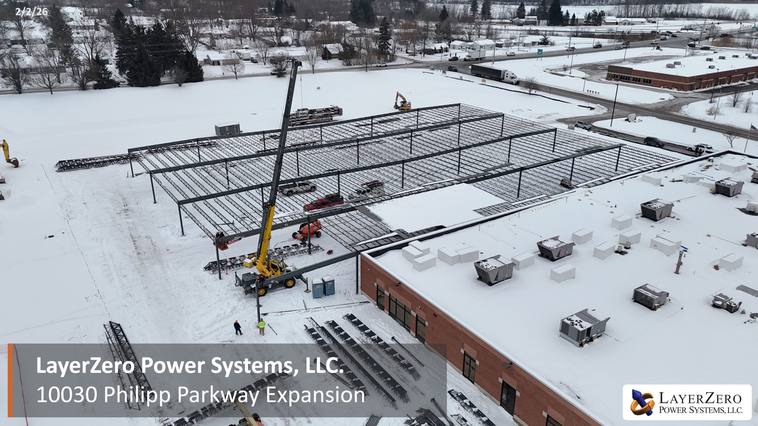 Crane installing large steel beams for LayerZero Power Systems Philipp Parkway expansion in winter.