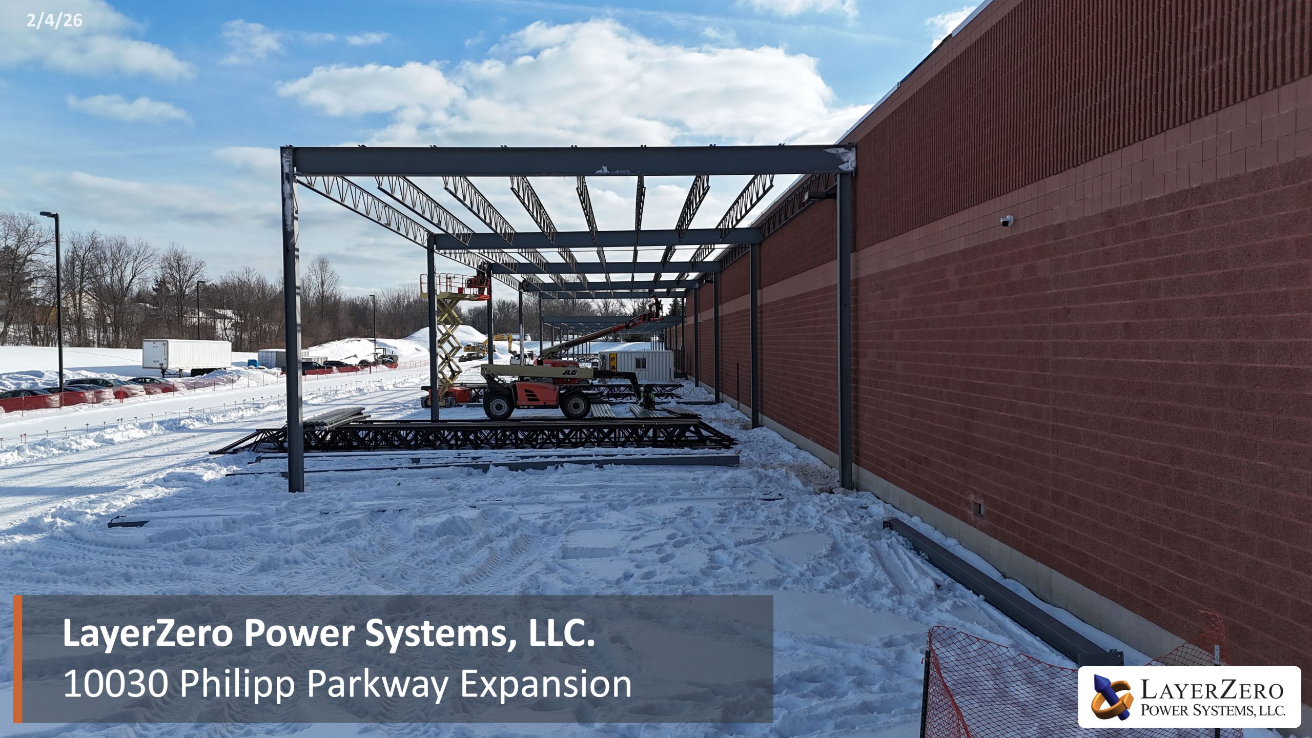 Construction crews assembling steel beams for LayerZero Power Systems Philipp Parkway expansion in snowy conditions.