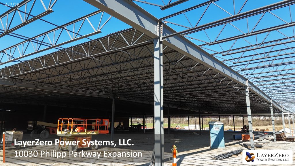 Interior view of LayerZero Power Systems expansion showing open steel roof trusses and structural framing during construction