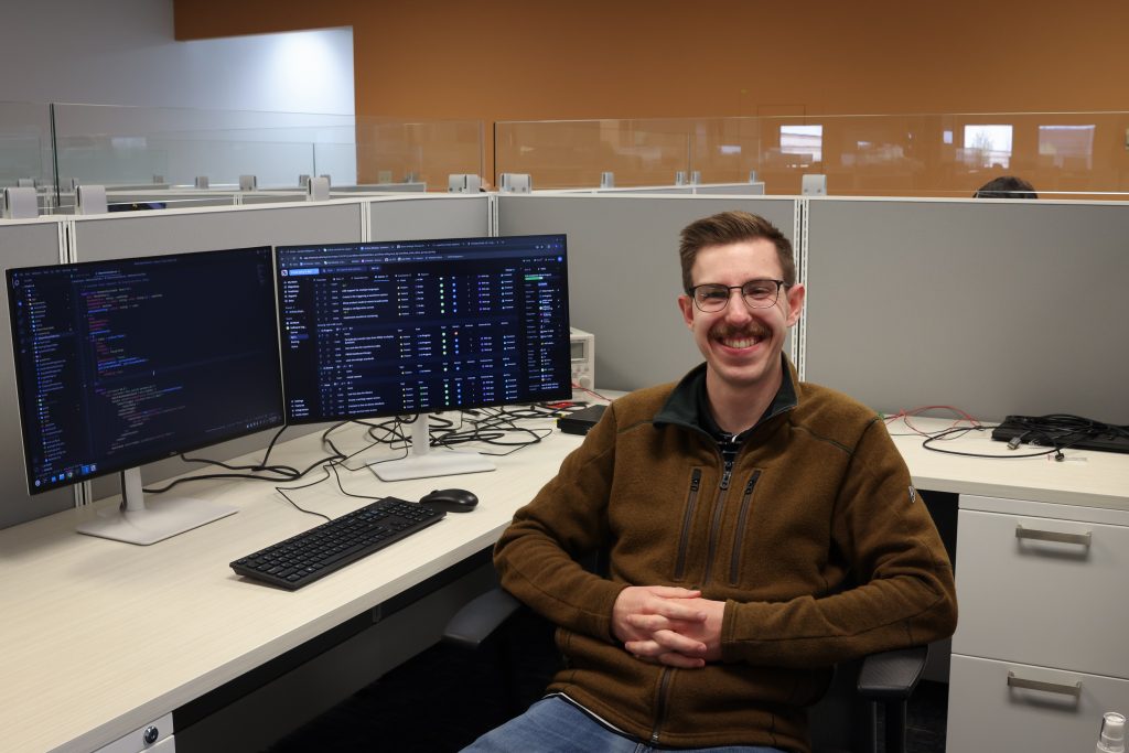 Engineer working at a workstation with multiple monitors displaying software and system data.