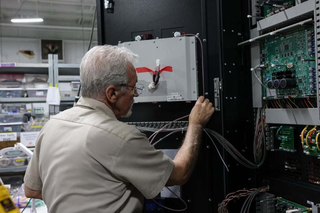 Senior technician routing and securing control wiring inside an electrical cabinet.
