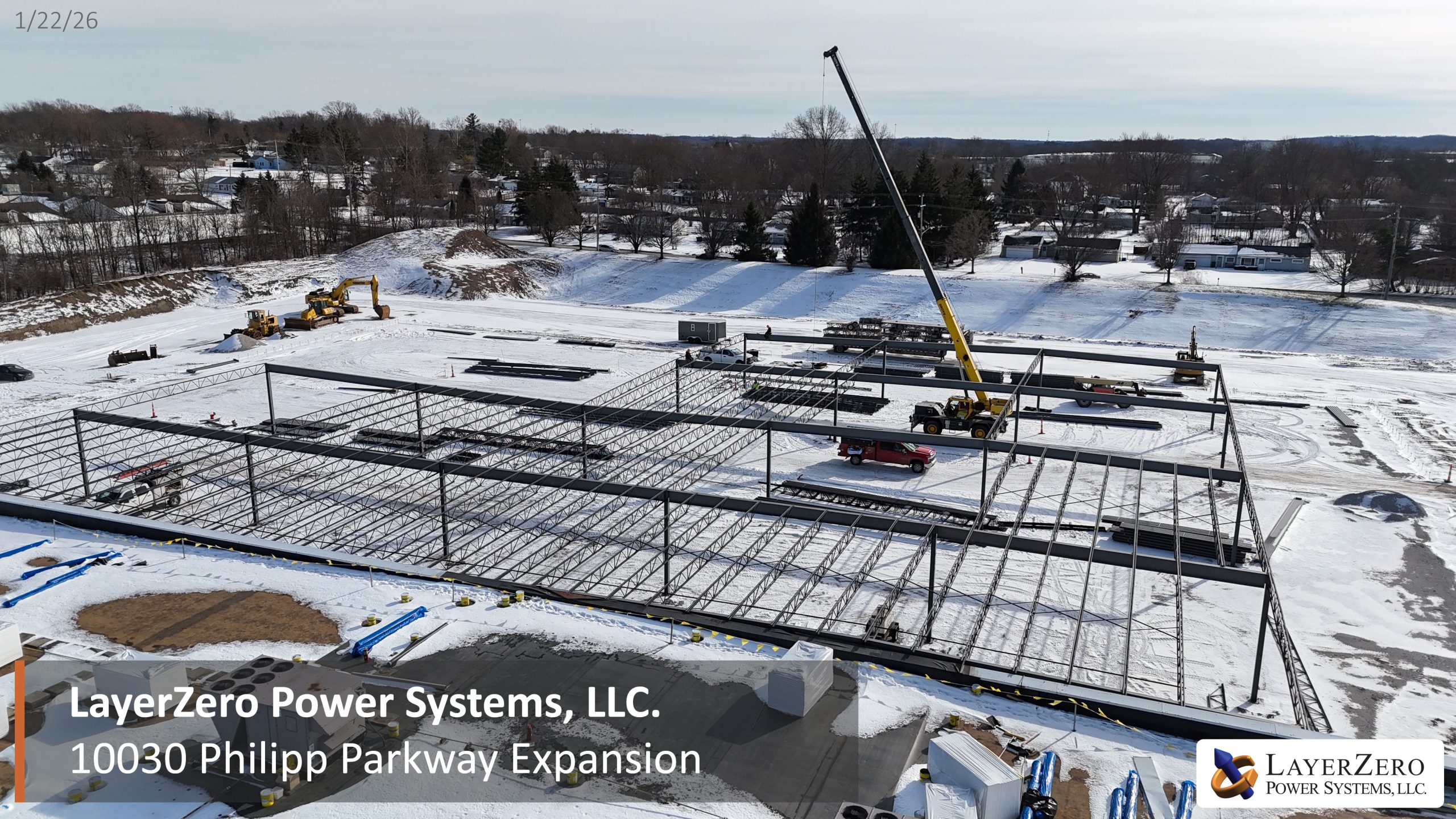 Aerial view showing structural steel framework, crane operations, and construction equipment at the LayerZero Power Systems Philipp Parkway expansion site.