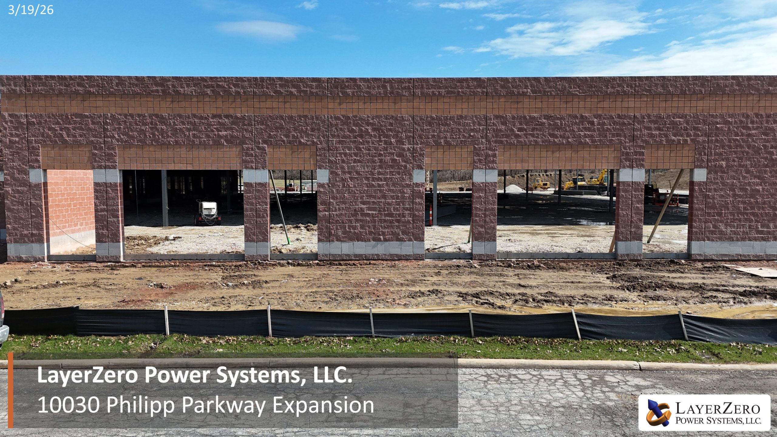 Exterior masonry progress on the LayerZero Power Systems expansion showing structural openings for future manufacturing access