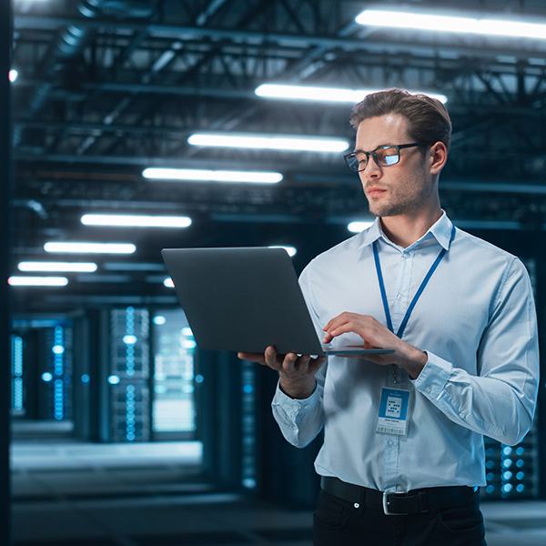 Engineer monitoring enterprise data center infrastructure using a laptop.
