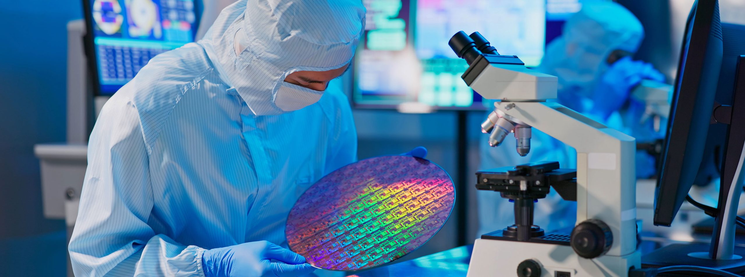 Semiconductor manufacturing technician inspecting silicon wafer in a cleanroom environment requiring reliable, mission-critical power